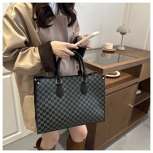 Detail of vintage patterned tote bag with gray M-print and gold metal hardware accents