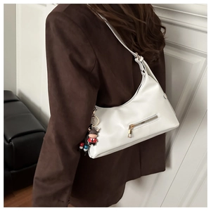Close-up of white PU leather hobo bag with metal zipper and cartoon bull keychain charm