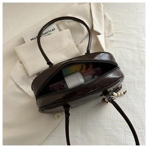 Detail view of dark brown glossy baguette bag with fashion embossing on white texture