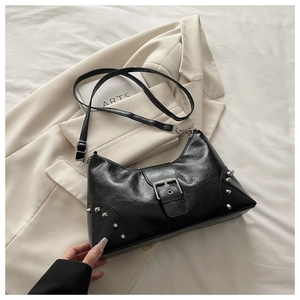 Detail of black shell bag with silver studs on beige blazer and white fabric base