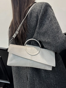 Gray crocodile texture handbag with silver ring handle and crossbody strap on a model