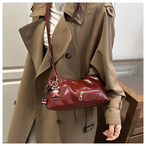 Detail of dark red glossy patent leather tote with metal zipper pocket and bull charm