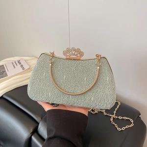Detail of light green lace evening bag with golden crown clasp and metal handle chain