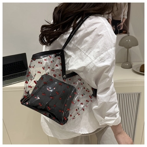 Detail of transparent PVC tote with cherry print and inner bag worn on shoulder