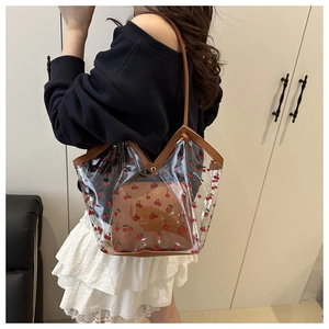 Detailed side view of a transparent cherry-print tote bag with a brown inner pouch