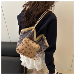 Detail of transparent PVC tote bag with cherry print and inner pouch worn by model