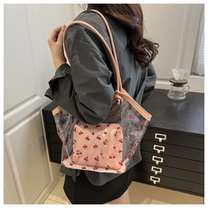 Vista dettagliata della borsa tote in PVC trasparente con stampe di ciliegie e manici rosa