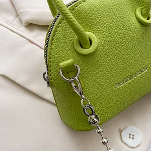 Detail of green shell bag with silver hardware hook and pebble leather texture
