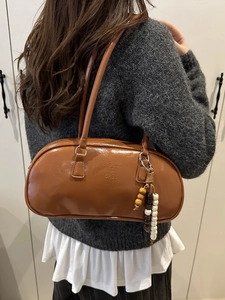 Brown leather cylindrical underarm bag with beaded tassel and embossed fashion text