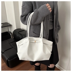 Détail du sac cabas blanc avec plis latéraux et un nœud décoratif à boucle dorée