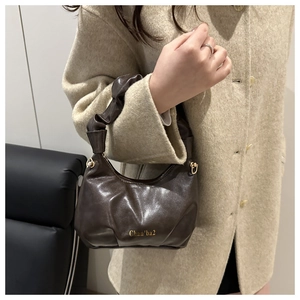 Close-up of a dark brown pleated mini handbag with a gold logo and soft faux leather texture