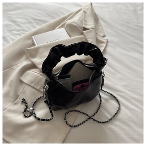 Detail view of black pleated handbag with silver chain strap and spacious inner storage