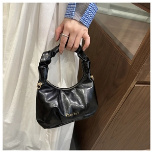 Detail of black pleated cloud bag with glossy finish and elegant gold zipper hardware