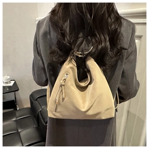 Shoulder bag in beige soft leather with decorative zipper and tassel detail on model