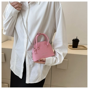 Borsa a conchiglia rosa con trama litchi e catena a sfere argentata indossata dal modello
