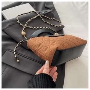 Close-up of brown quilted handbag with gold chain strap and metal ball accessory