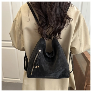 Detail of black vintage matte backpack with metal zippers and elegant tassels