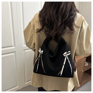 Détail du sac cabas en toile noire avec fermetures éclair et nœuds en ruban blanc