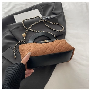 Detail of caramel quilted suede handbag with black leather trim and gold chain strap