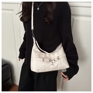 Detail shot of a cream white shoulder bag featuring a silver metal buckle and leather strap