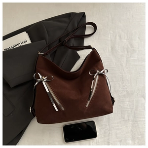 Détail du sac hobo marron foncé avec finition mate et breloques de fermeture en nœud
