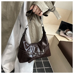 Detail of dark brown patent leather shoulder bag with buckle straps and silver hardware