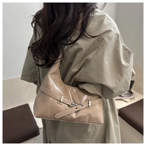 Detail of khaki patent leather underarm bag with silver grommet belt and buckle