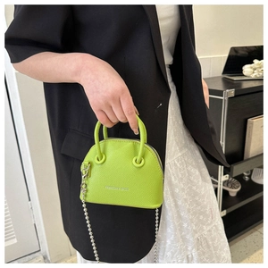 Dettaglio borsa a conchiglia verde neon con trama litchi e catena in metallo