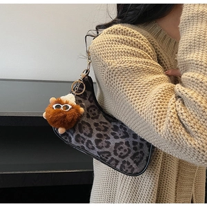 Detail of leopard print crescent bag with cute plush pendant on a knit sweater