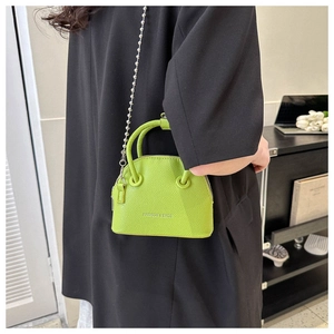 Dettaglio borsa a conchiglia verde neon con trama litchi e catena a sfere argento