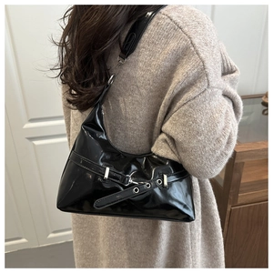 Detail of a black glossy underarm bag with silver buckle and wide shoulder strap