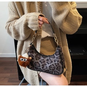 Macro shot of leopard print faux suede bag with gold chain and plush charm detail