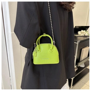 Dettaglio borsa a conchiglia verde fluo con catena argento e logo con testo bianco