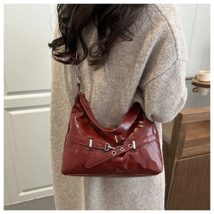 Detail view of burgundy patent leather underarm bag with silver buckle and adjustable strap