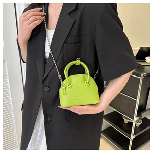 Dettaglio della mini borsa a conchiglia verde lime con catena d'argento e logo moda