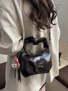 Brown pleated faux leather handbag with chain strap and cute plush charm on model