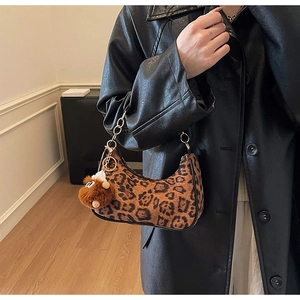 Detailed view of leopard print shoulder bag with plush charm and metal chain strap
