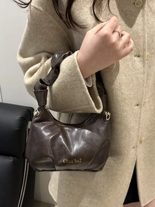 Minimalist brown faux leather crescent handbag with pleated handle on a wool coat model