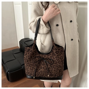 Close-up of leopard print shoulder bag with black leather base and gold-tipped bow detail