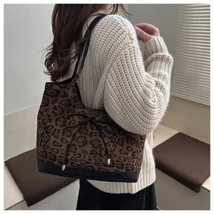 Detail view of large leopard print tote bag with black bow and metal accents