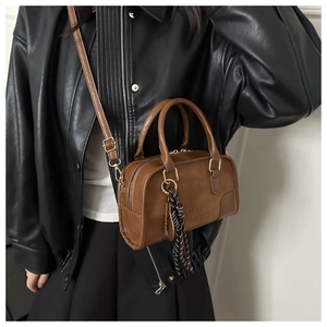 Dettaglio della borsa Boston marrone vintage con logo e accessorio foulard a pois