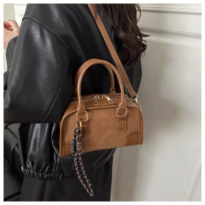 Dettaglio borsa Boston marrone in pelle con nappa intrecciata e finiture dorate