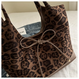Close-up of leopard print faux fur texture with a delicate bow knot and leather trim