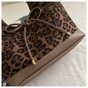 Detail of leopard print velvet texture with brown leather stitching and golden drawstring tips