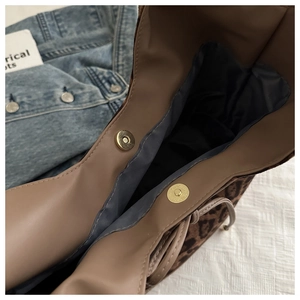 Detailed close-up showing dual gold magnetic buckles and leopard print lining of the tote bag