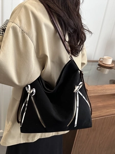 Grand sac hobo noir avec nœuds en ruban et bandoulière en cuir marron sur modèle