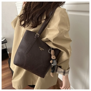 Detail of dark brown pebble leather tote bag with rabbit charm and adjustable strap