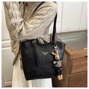 Detail of black leather tote bag with gold lettering and cute bunny doll charm