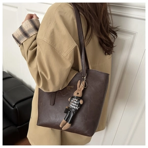 Detail of dark brown leather tote bag with gold logo and stylish rabbit charm accessory