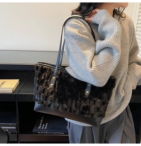 Detail of black faux fur and leather contrast bucket bag on a model in a gray sweater